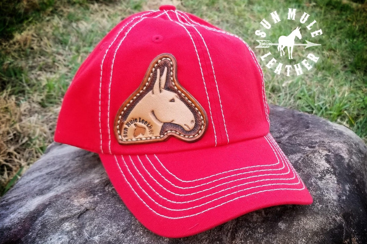 Hand tooled mule head shaped leather patch on a red soft hat.