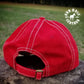 Back view of hand tooled mule head shaped leather patch on a red soft hat.