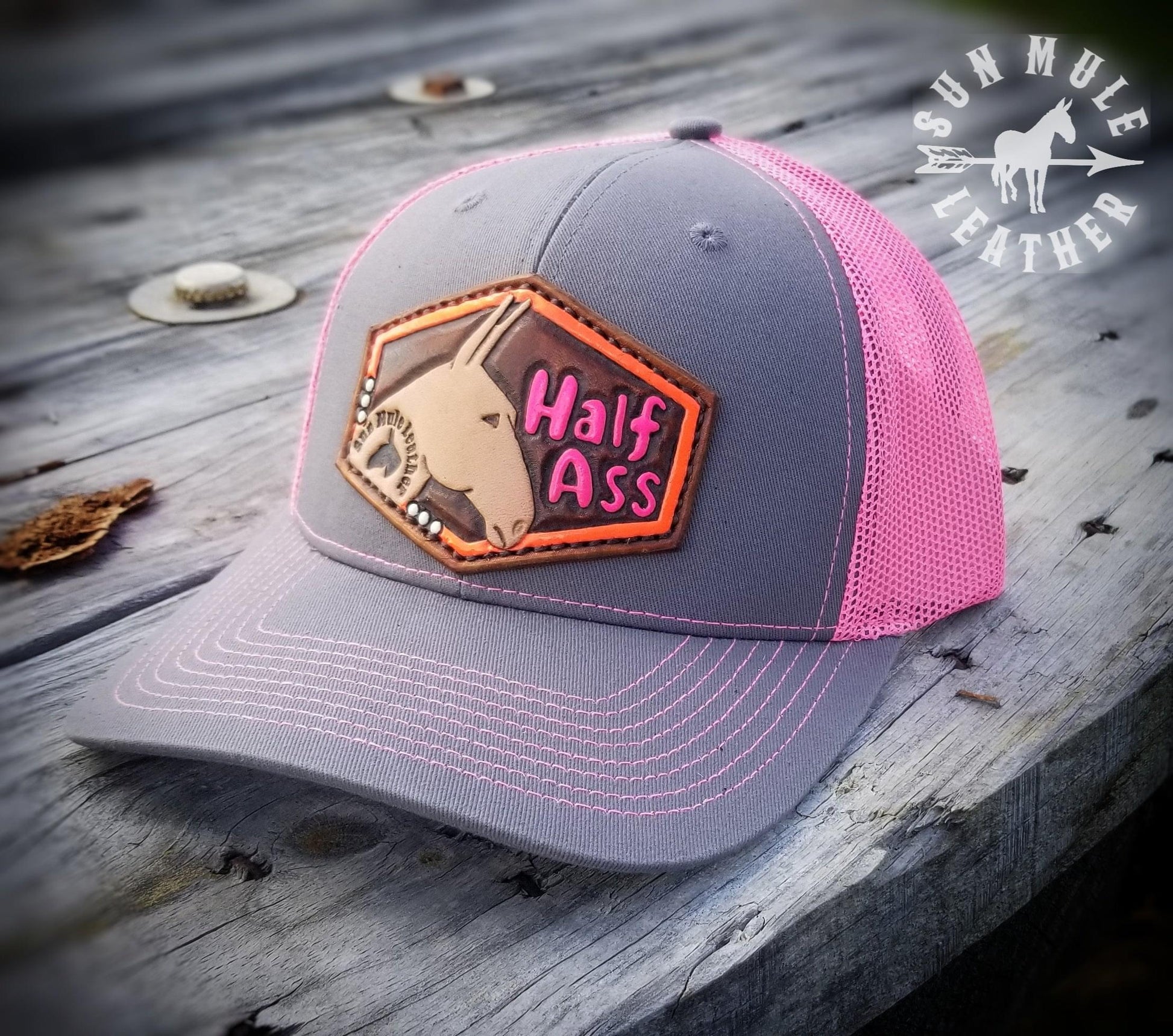 Alternate view of pink trucker mule hat, leather hand tooled patch depicting a mule and the words "half ass".