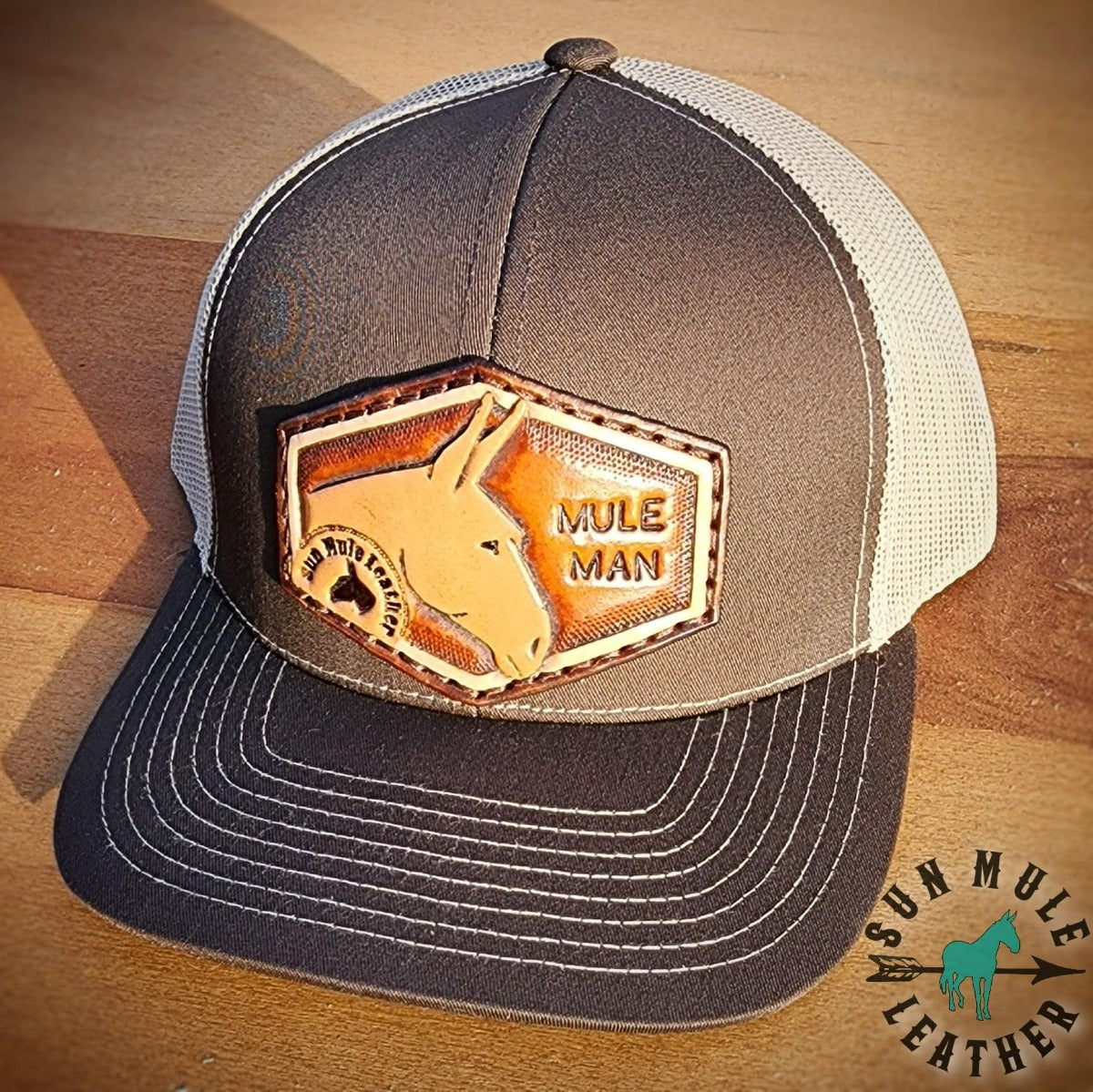 Brown trucker hat with handtooled leather patch of a mule and the stamped letters "Mule Man" cap.